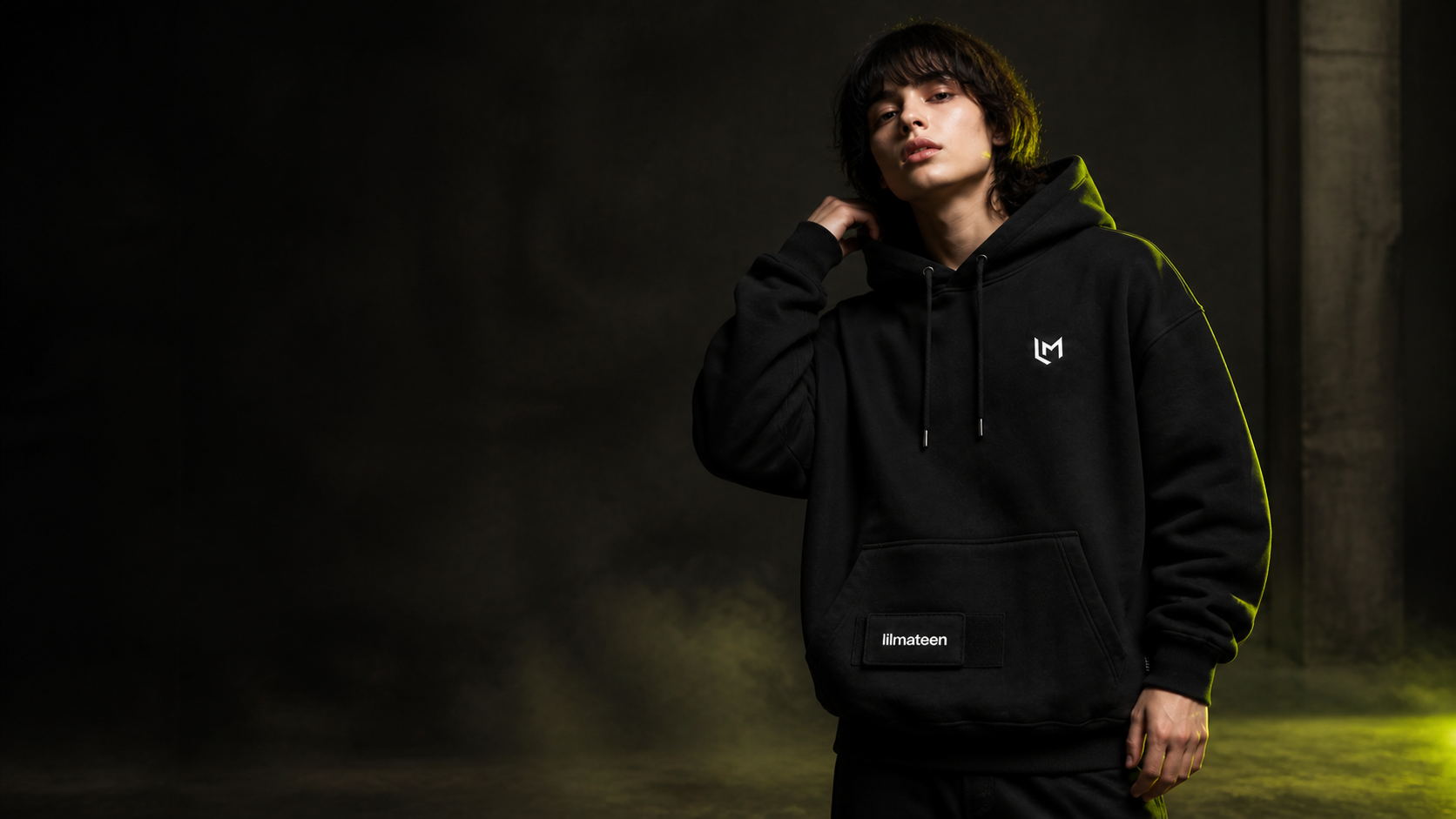 Model wearing the black LILMATEEN hoodie with chest logo and original pocket patch